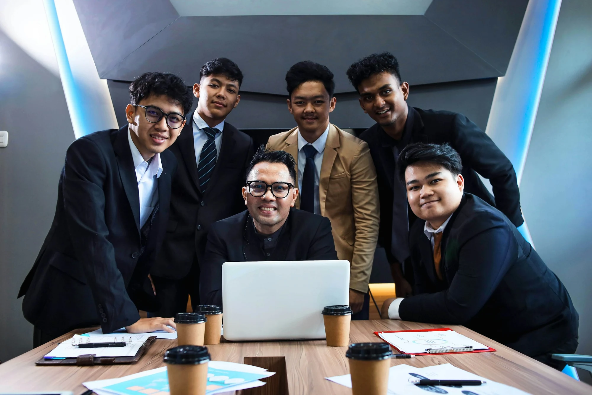 A Malaysian business team gathered around a laptop