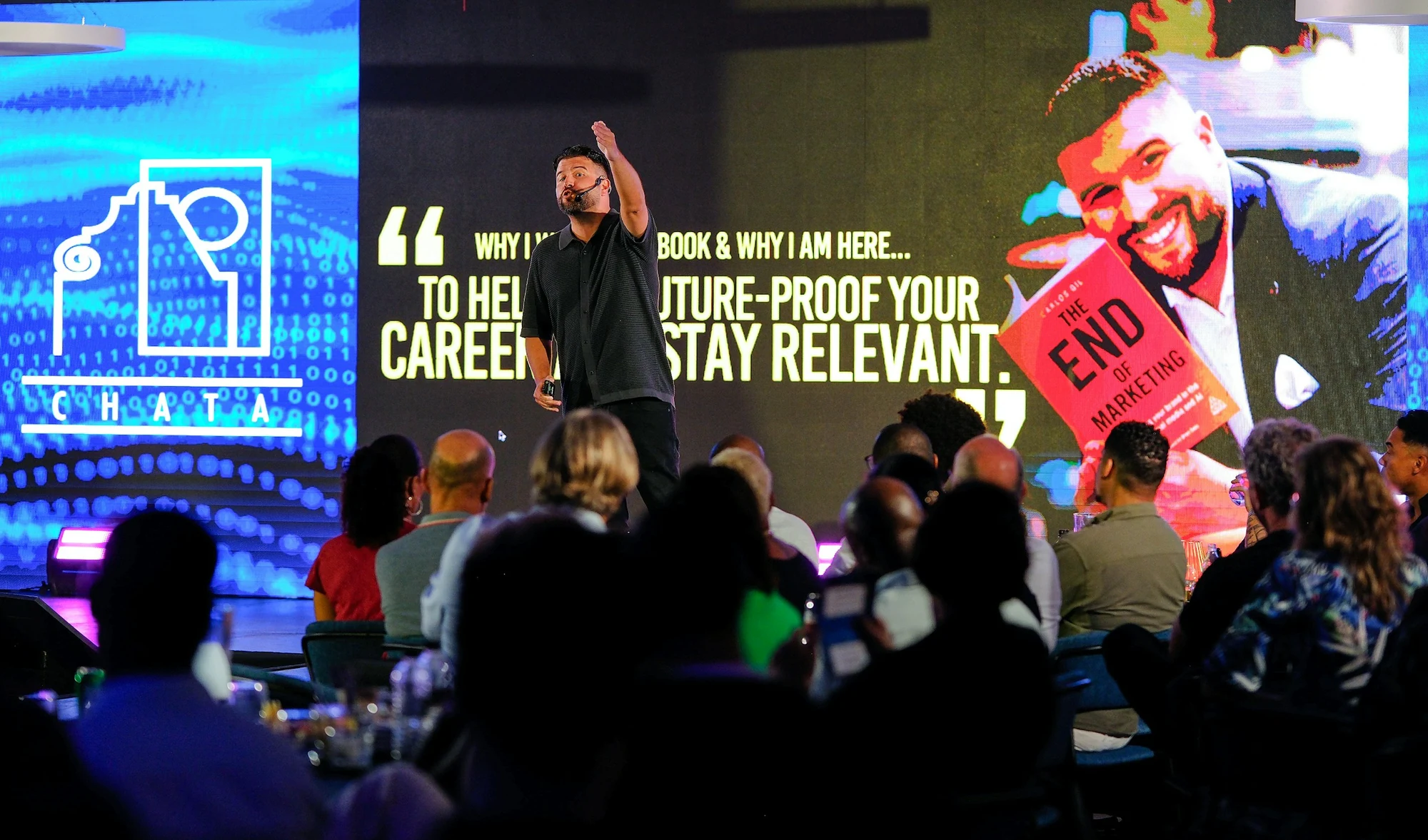 A speaker on stage in front of large screens